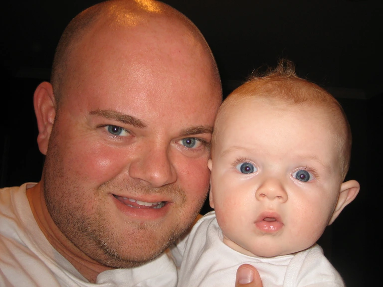 Chris Hughes holding his son as a baby