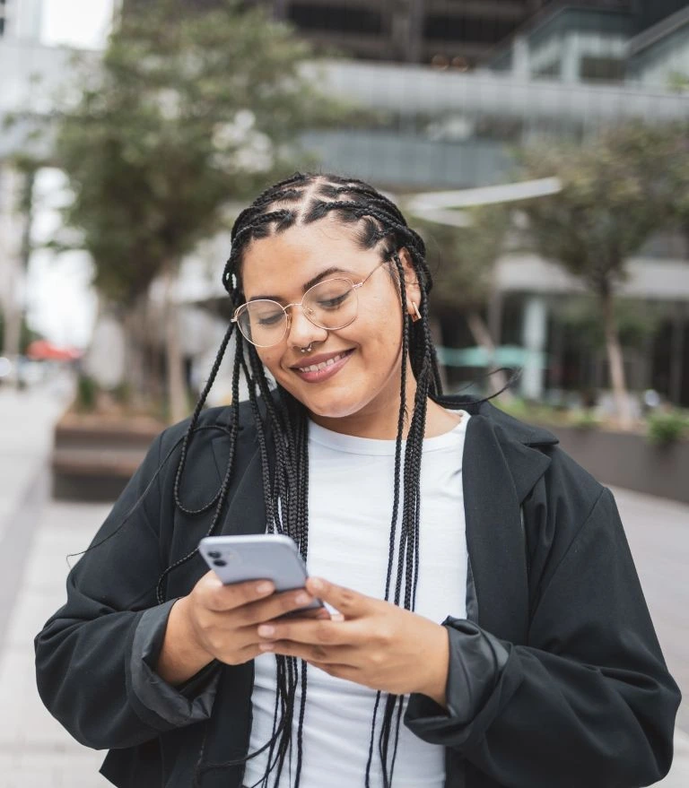 woman on a downtown street using her phone to apply for an installment loan in Texas